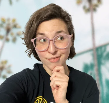 About a woman wearing glasses in front of palm trees.