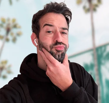 About Us: A man with a beard is thoughtfully putting his hand on his face.